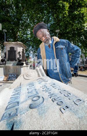 Lo scrittore e musicista Simbarashe Tongogara sormonda una sezione di zoccolo rotto nel sito della statua rovesciata di Edward Colston a Bristol - 8 giu Foto Stock