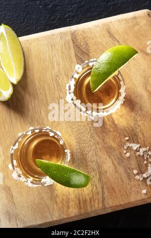Golden tequila scatti con cerchioni di sale e fettine di lime, overhead close-up shot Foto Stock