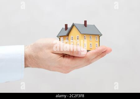 Piccola casa gialla miniatura in mano Foto Stock
