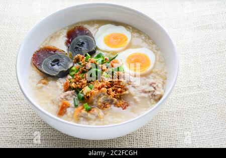 Congee, porridge di riso con maiale tritato, uova bollite e uova da secolo, ottimo per la colazione. Foto Stock