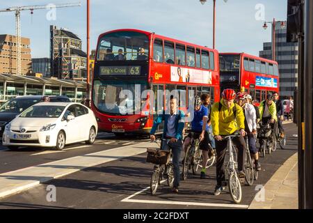 London, England - May 4, 2016: Cyclistswait at a traffic signal beside double-decker buses on London's new Cycle Superhighway on Blackfriars Bridge Foto Stock