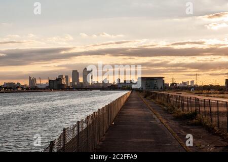 Londra, Inghilterra, Regno Unito - 31 luglio 2010: Il sole tramonta dietro lo skyline del quartiere commerciale Docklands di Londra e i wastgrounds dei Royal disusati Foto Stock