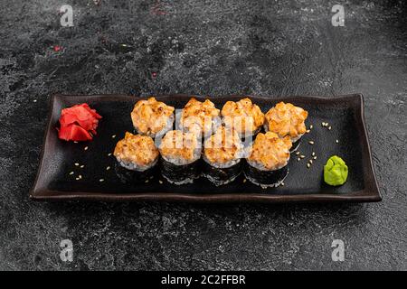 Set di panini di sushi al forno con wasabi e zenzero su sfondo nero. Cucina orientale Giapponese Foto Stock