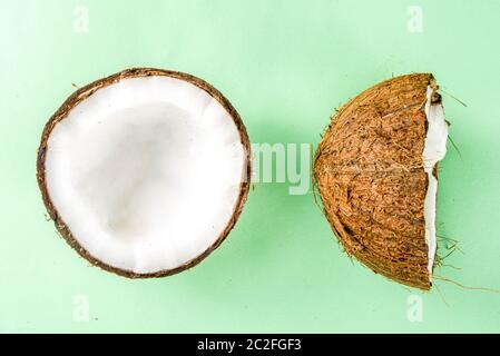 Isolato fresco di cocco grezzo su sfondo bianco. Metà delle noci di cocco su un tavolo verde chiaro Foto Stock