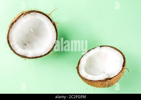 Isolato fresco di cocco grezzo su sfondo bianco. Metà delle noci di cocco su un tavolo verde chiaro Foto Stock