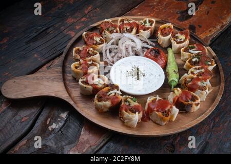 Il Beyti kebab turco è servito con verdure alla griglia e salsa allo yogurt, isolato su un rustico tavolo di legno Foto Stock