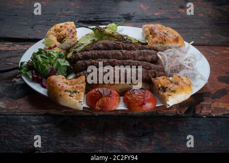 Kebab di agnello Mardin turco con pane e verdure isolato su rustico tavolo di legno Foto Stock