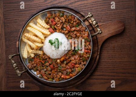 Carne di agnello di cibo turco, kavurma sac con riso e patatine fritte isolate su tavola di legno Foto Stock