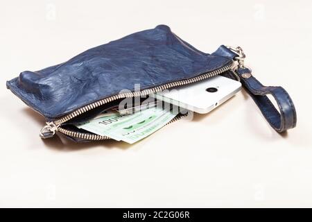 Aprire blu braccialetto in pelle borsetta borsa con carte di credito, smartphone e le banconote in euro sul marrone pallido tabella Foto Stock