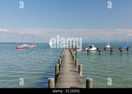 Chiemsee con barche a vela, molo e Alpi, Gstadt, alta Baviera, Germania Foto Stock