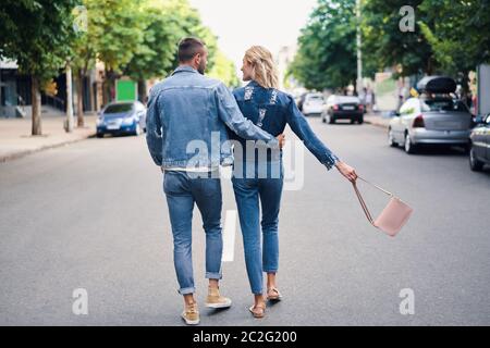 Vista posteriore della coppia che si agganata a piedi sulla strada Foto Stock