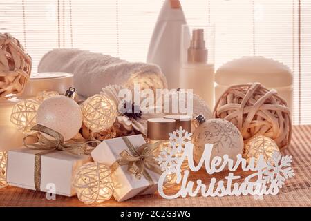 Spa Still Life con creme cosmetiche, asciugamano, scatole regalo e ornamenti di Natale in piedi su tappeto di bambù. Natale stile di vita sano, cura del corpo, spa tr Foto Stock