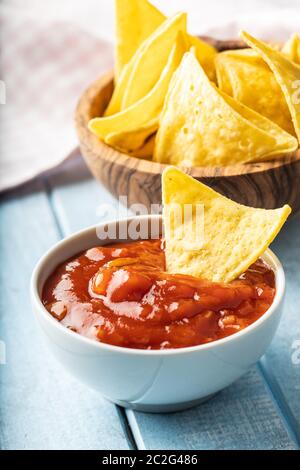 Il mais nacho chips e pomodoro dip. Giallo tortilla chips e salsa sul vecchio tavolo blu. Foto Stock