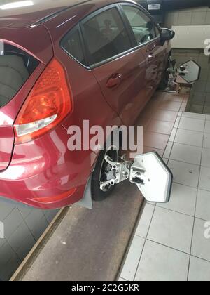 Auto luminoso cremisi in una stazione di servizio. Processo di allineamento della convergenza Foto Stock