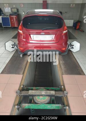 Auto luminoso cremisi in una stazione di servizio. Processo di allineamento della convergenza Foto Stock