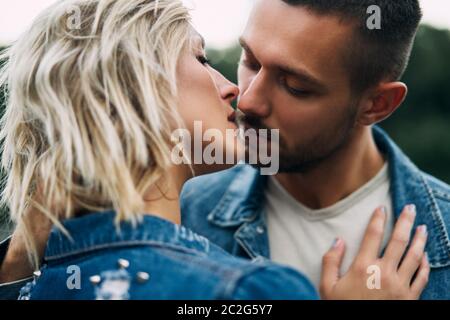 Giovane coppia amorosa baciarsi e godere la compagnia degli altri all'aperto Foto Stock