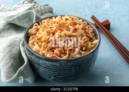 Istante di spaghetti ramen con la carota e una salsa, un close-up con bacchette su uno sfondo blu Foto Stock
