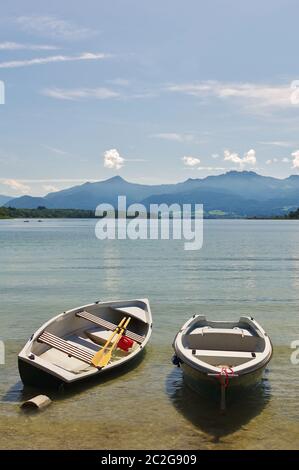 Barche a remi, legate alla riva, Chiemsee, sullo sfondo le Alpi, Chiemgau, alta Baviera, Germania Foto Stock