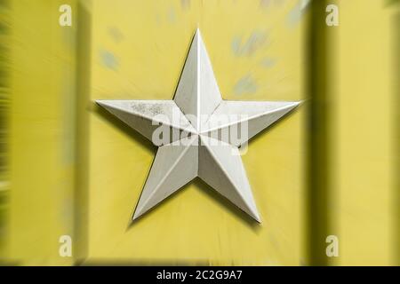 Argento metallo cinque stelle sovietiche puntato su uno sfondo sfocato di colore giallo verdolino chiaro Foto Stock
