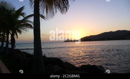 Tramonto incredibile a Curtain Bluff, Antigua, Caraibi - palme e calmo mare guardando il sole scendere nella vacanza migliore Foto Stock