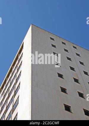 vista prospettica d'angolo di un vecchio edificio bianco in cemento degli anni '60 contro un cielo blu Foto Stock