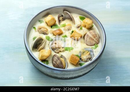 Clam Chowder, decorate con prezzemolo fresco e crostini, su uno sfondo blu Foto Stock