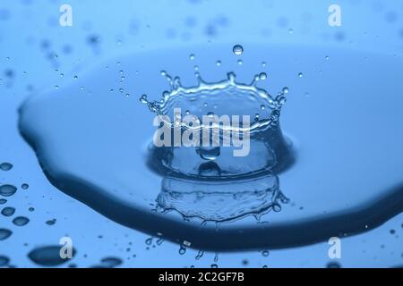 spruzzi d'acqua sul vetro su sfondo blu Foto Stock
