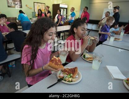 Austin Texas USA, aprile 20 2016: Gli studenti della scuola media mangiano fette di pizza e insalata nella caffetteria della scuola. ©Bob Daemmrich Foto Stock