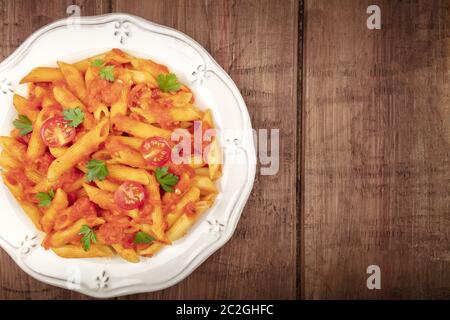 Primi piano con pasta Penne. Pasta con salsa di pomodoro e prezzemolo, sparato dall'alto su uno sfondo di legno rustico scuro con un posto per Foto Stock