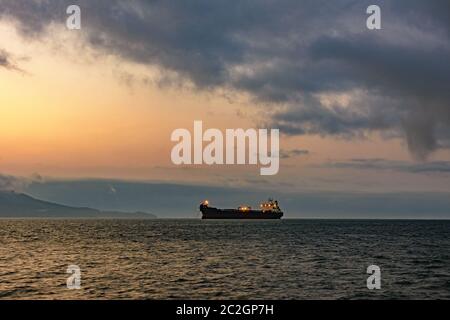 Nave da carico ancorata nelle acque dell'isola di Ilhabela al tramonto Foto Stock