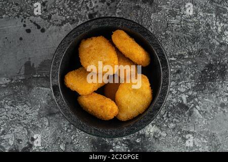 Una porzione di pepite di pollo gustose e croccanti su sfondo grigio. Un popolare fast food a base di carne di pollo Foto Stock