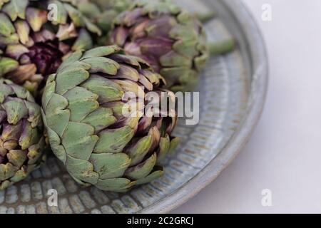 Immagine di primo piano dei carciofi su un vassoio di metallo rustico composizione orizzontale. Profondità di campo poco profonda. Foto Stock