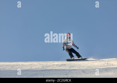 Snowboarder scendendo lungo la pendenza, copia spazio nel cielo Foto Stock