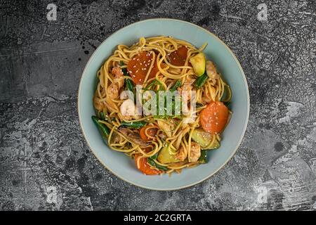 Vista dall'alto sulla appetitosa cucina asiatica pollo e verdure udon noodles wok sul tavolo di legno, orizzontale Foto Stock