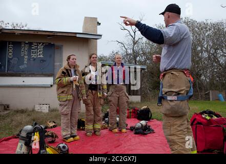 Austin Texas USA, febbraio 4 2014: Studenti femminili della LBJ High School Fire Training Academy ascoltano il loro istruttore mentre si preparano a mettere in pratica le abilità antincendio durante gli esercizi di addestramento. Gli studenti laureati nel programma biennale avranno diritto alla certificazione EMT per i tecnici medici di emergenza e possiederanno competenze avanzate in materia di estinzione degli incendi. ©Bob Daemmrich Foto Stock