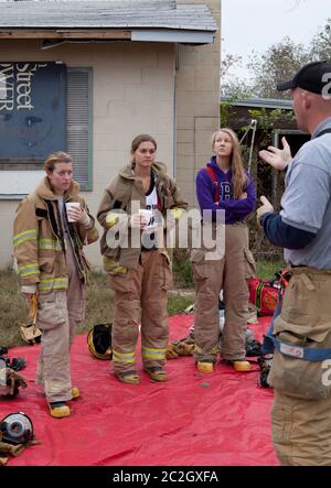 Austin Texas USA, febbraio 4 2014: Studenti femminili della LBJ High School Fire Training Academy ascoltano il loro istruttore mentre si preparano a mettere in pratica le abilità antincendio durante gli esercizi di addestramento. Gli studenti laureati nel programma biennale avranno diritto alla certificazione EMT per i tecnici medici di emergenza e possiederanno competenze avanzate in materia di estinzione degli incendi. ©Bob Daemmrich Foto Stock