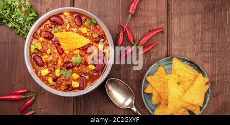 Un panorama di cibo messicano. Chili con carne, peperoncini, foglie di coriandolo e nachos Foto Stock