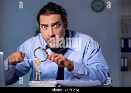 Dipendente affamato che lavora tardi in ufficio Foto Stock