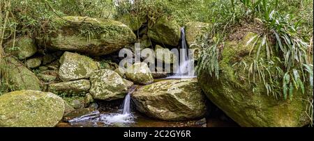 Piccola cascata panoramica tra la vegetazione della foresta pluviale dell'isola di Ilhabela Foto Stock