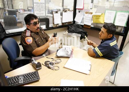 Brownsville Texas USA, 26 2014 settembre: Il vice Jorge Marquez della Cameron County si interroga su un sospetto immigrato illegale nella prigione della contea, dove è stato portato dopo essere stato catturato con 230 libbre di marijuana sul retro di un camion pick-up. ©Bob Daemmrich Foto Stock