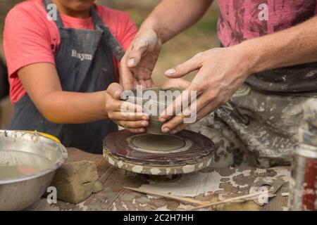 Primo piano di una mano di Potter scolpisce un caraffa di creta su una ruota di Potter Foto Stock