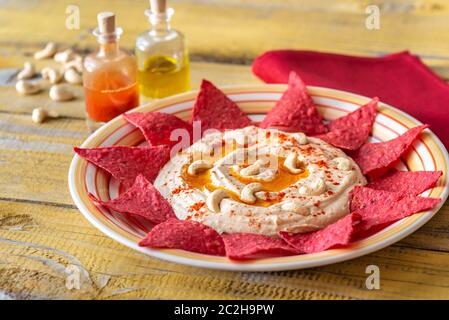 Hummus con tortilla chips sul tavolo di legno Foto Stock