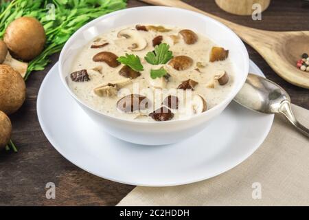 Zuppa di funghi con champignon e pepe al buio su un rustico sfondo di legno, fuoco selettivo Foto Stock