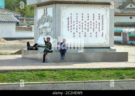 Kaesong, Corea del Nord - 5 maggio 2019: I bambini locali salutano e si fermano in un vialetto di accesso in un villaggio vicino a Kaesong Foto Stock