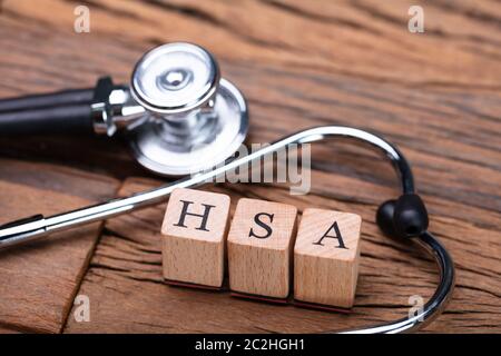 Il sistema HSA Health Conto di risparmio dei blocchi di legno vicino a uno stetoscopio sul tavolo di legno Foto Stock