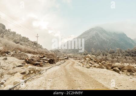 Una lunga strada dritta che conduce verso una montagna innevata nel Kashmir invernale India Foto Stock