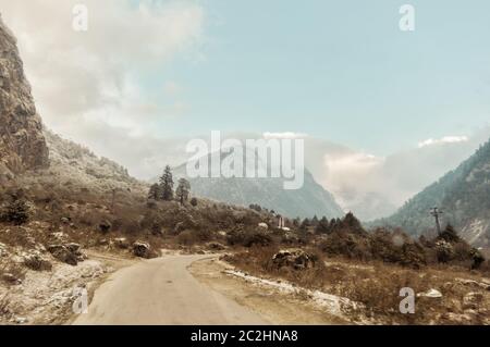 Una lunga strada dritta che conduce verso una montagna innevata nel Kashmir invernale India Foto Stock