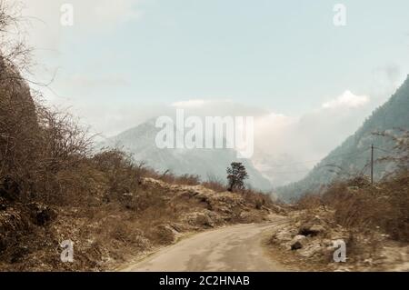 Una lunga strada dritta e talvolta tortuosa che conduce verso una montagna innevata nel Kashmir India invernale Foto Stock