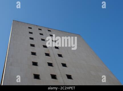 vista prospettica d'angolo di un vecchio edificio bianco in cemento degli anni '60 contro un cielo blu Foto Stock