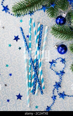 Le Cannucce con vari pattern in colore blu per il Natale o la festa di Capodanno. Luce brillante sfondo blu con accessori di festa e di Abete rami. Parte superiore Foto Stock